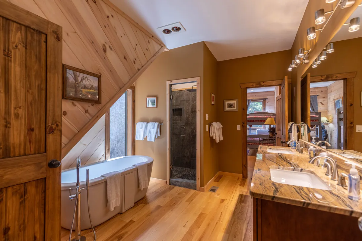 A modern spa-inspired bathroom with a freestanding bathtub, double sink vanity, and a glass-enclosed walk-in shower. The design is sleek, tranquil, and indulgent—ideal for unwinding after a day in the mountains.