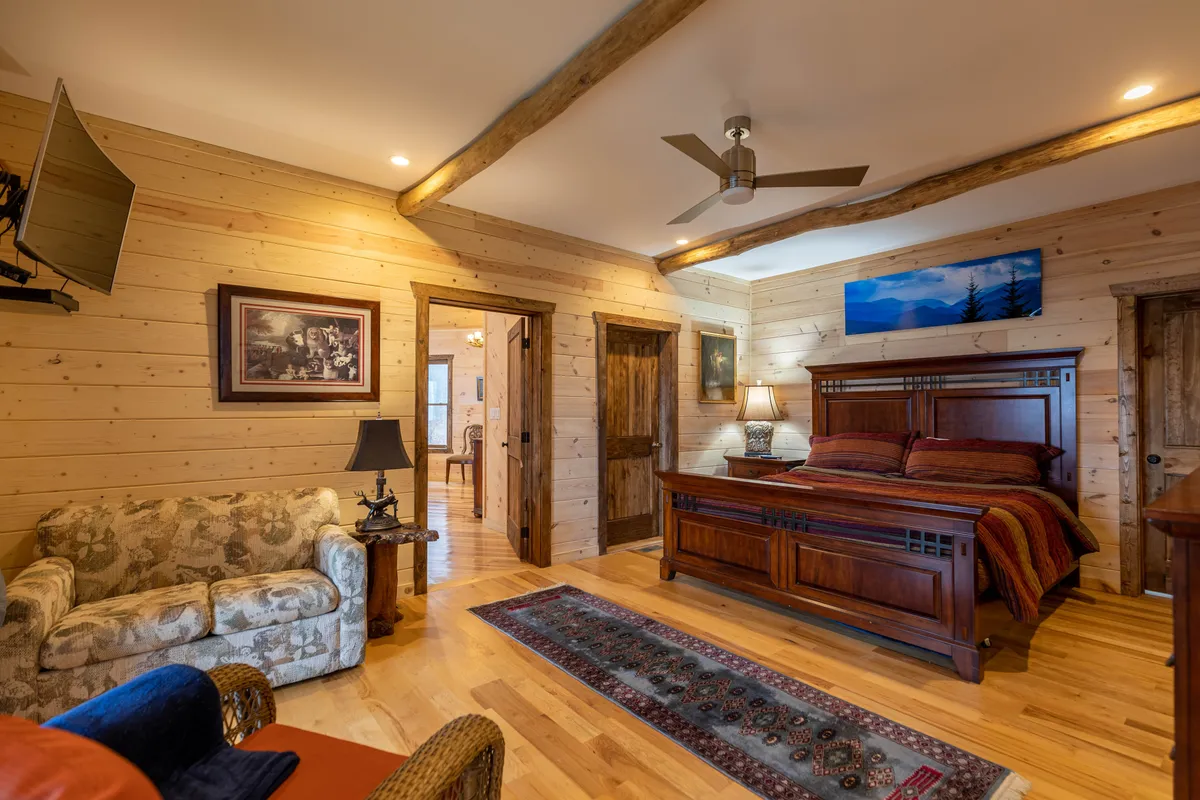 A tranquil guest suite with a comfortable bed featuring decorative throw pillows, wooden furnishings, a sofa, and tasteful wall art. The space exudes comfort and calm, suitable for unwinding after a day of excitement.